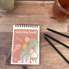 cahier de coloriage Floral sur une table avec crayons de coloriage, une infusion et une bougie