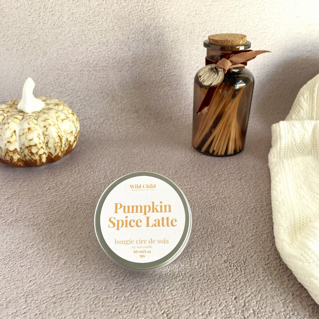 Bougie pumpkin spice latte focus sur le packaging métallique avec une décoration citrouille et un plaid et des allumettes