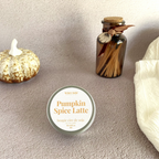 Bougie pumpkin spice latte focus sur le packaging métallique avec une décoration citrouille et un plaid et des allumettes